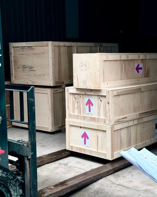 Numbered wooden furniture crates marked with this-way-up arrows, staged on a pallet ready for container loading