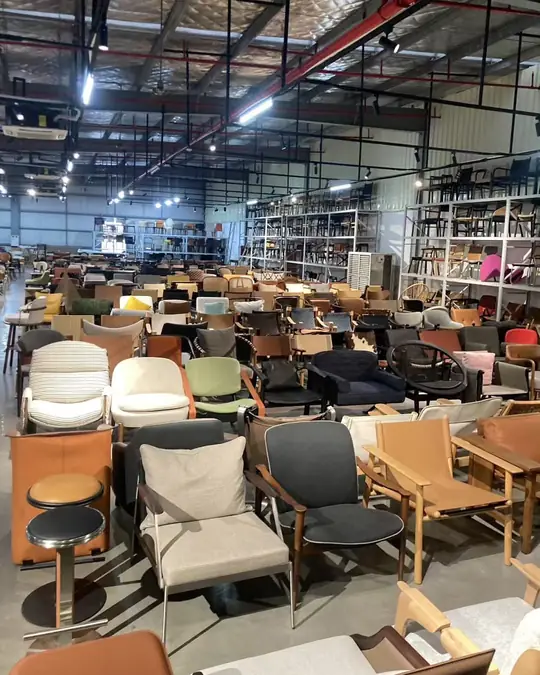 A showroom floor packed with armchairs in cream, sage green, charcoal and tan, racking of chairs rising behind them