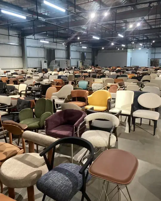 A wide view down a showroom of upholstered dining chairs in many colours, arranged in long rows under an industrial ceiling